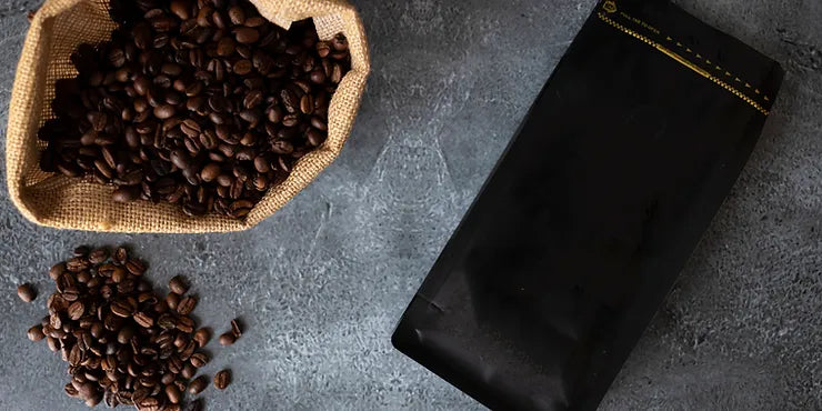 Open sack of coffee beans beside a sealed bag, showing bulk coffee bean buying